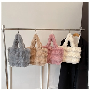 Close-up of plush faux fur tote bags in grey, khaki, pink and white hanging on a rack