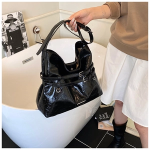 Dettaglio macro della borsa hobo in vernice nera con fibbie metalliche argentate