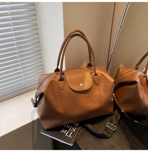Detailed macro of caramel brown lychee leather Boston bag with woven shoulder strap