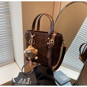 Macro shot of dark brown frosted suede bucket bag with vintage monogram and plush charm