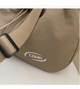 Dettaglio della trama in nylon kaki e del ricamo TZIMEI su una borsa a tracolla grande