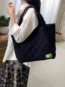 Black quilted tote bag with green logo label and diamond stitching for women