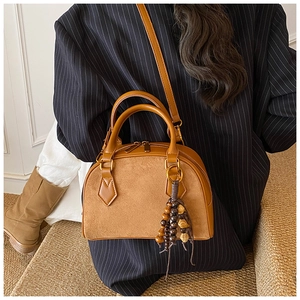Close-up of vintage brown shell bag with suede stitching and wooden bead tassel