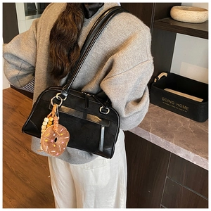 Detail of matte black suede shoulder bag with colorful donut plush charm and dual straps