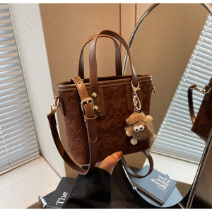 Detail of vintage brown bucket bag with quilted monogram and plush charm pendant