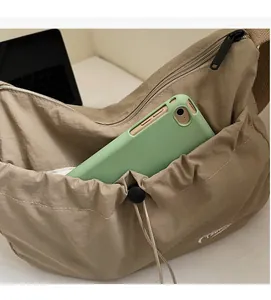 Dettaglio della borsa a tracolla in nylon kaki con tasca esterna a coulisse e smartphone