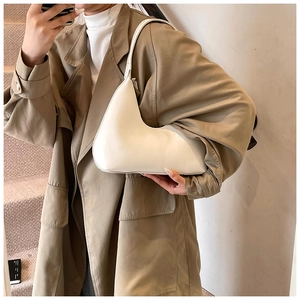 Sac hobo blanc asymétrique porté avec un trench-coat pour un look élégant et moderne