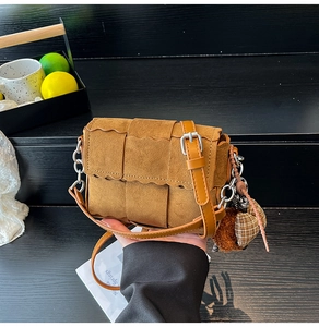 Close-up of brown woven crossbody bag featuring scalloped edges and plush heart charms