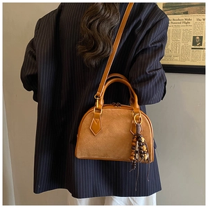 Detail of caramel boston bag with suede patchwork and unique wooden bead tassel