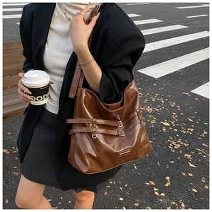 Borsa tote in pelle lucida marrone indossata da modella in un contesto urbano