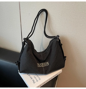 Detail of black checkered shoulder bag featuring white Fashion logo and knot strap details
