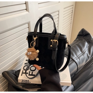 Detail of black quilted bucket bag with matte finish and cute brown sheep plush charm
