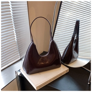 Détail du sac hobo en cuir brillant marron foncé sur livre avec jeux d'ombre