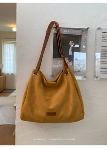 Detail of a large yellow tote bag with adjustable brown leather strap and matte texture