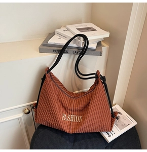 Close-up of brown plaid canvas tote with FASHION embroidery and black rope strap
