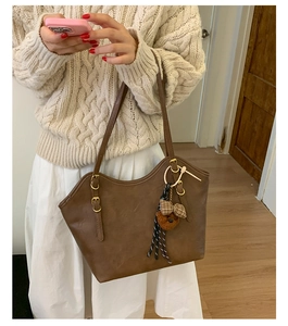 Detail einer dunkelbraunen Leder-Tote mit Plüschbären-Anhänger und goldener Schnalle