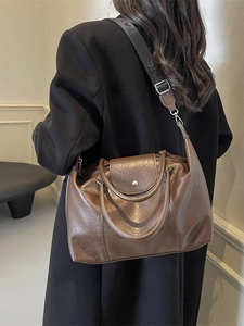 Vintage dark brown tote bag with wide logo strap shown on a model in a black coat