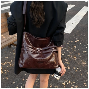 Borsa a secchiello in pelle marrone scuro con fibbia in metallo su un blazer nero