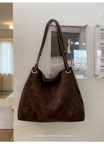 Close-up of vintage brown suede tote bag with metallic buckle and leather brand tag