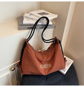 Detailed close-up of brown plaid hobo bag with a black rope handle and fashion embroidery