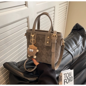 Detail of grey suede tote bag with G-pattern prints, leather trim and plush doll charm