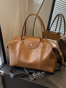Vintage brown leather tote bag with dual handles and black strap in an indoor setting