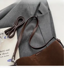 Detail of reinforced stitching and brown suede texture on a large hobo bucket bag
