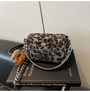Detail of leopard print woven square bag with silver chain and cute dog plush charm
