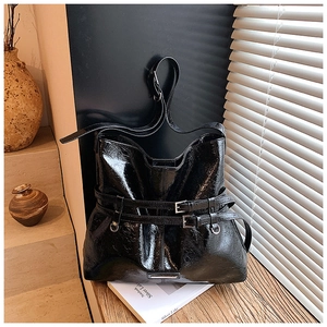 Dettaglio della borsa tote in vernice nera con fibbie metalliche e texture lucida increspata
