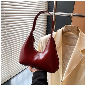 Gros plan d'un sac demi-lune rouge foncé en cuir avec texte embossé et fermeture éclair