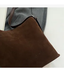 Close-up of brown suede tote bag with embossed fashion text and soft matte leather texture