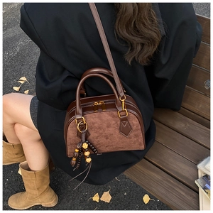 Detail of dark brown patchwork bag with leather texture and wooden bead tassel ornament