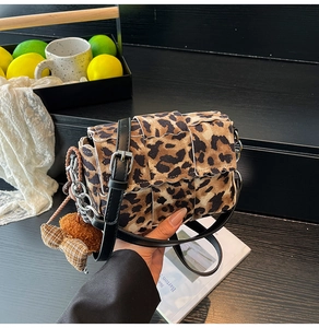 Detail of leopard print crossbody bag with woven texture and cute plush bear charm