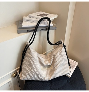 Detail of checkered tote bag featuring yellow Fashion embroidery and black rope handles
