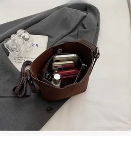 Detail view of brown matte bucket bag showing spacious interior with pockets and strap