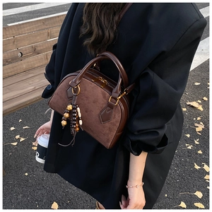 Detail of dark brown suede pillow bag with wooden bead tassel and gold-tone zipper