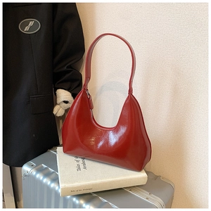 Détail du sac hobo en cuir verni rouge brillant avec fermeture éclair sur valise