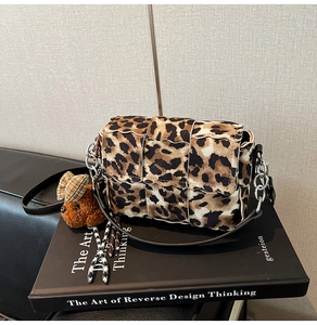 Detail of leopard print crossbody bag with silver chain strap and plush bear charm decoration