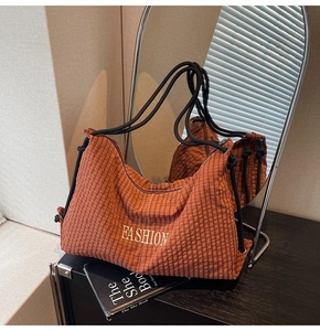 Close-up of checkered canvas shoulder bag with fashion text and rope strap detail