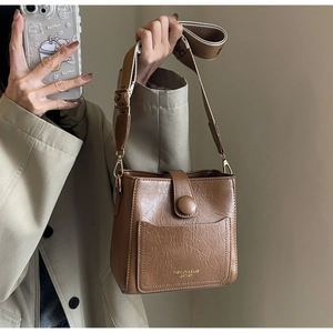 Détail du sac seau marron foncé avec texture plissée et large bandoulière en tissu