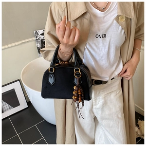 Close-up of black suede and leather pillow bag with gold hardware and tassel detail