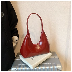 Détail du sac hobo en cuir verni rouge brillant avec une texture lisse et élégante