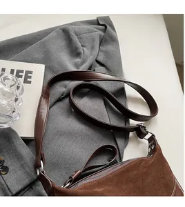 Detail view of the retro brown suede texture and smooth synthetic leather strap of the saddle bag