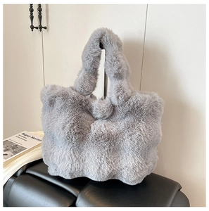 Detail of soft grey faux fur tote bag showing plush texture on a black leather bench