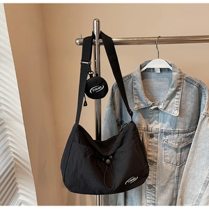 Dettaglio della borsa a mezzaluna in nylon nero con tracolla regolabile e portamonete