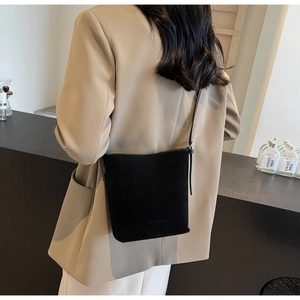 Minimalist matte black crossbody bag with slim leather strap shown on a model