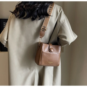 Vue détaillée d'un sac seau marron avec une large bandoulière à motifs réglable
