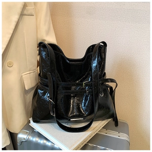 Vista dettagliata della borsa tote nera lucida con fibbie metalliche e spallacci