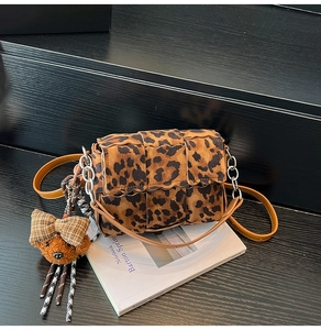 Detail of leopard print crossbody bag with chain strap and teddy bear charm on a magazine