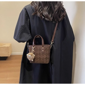 Detail of vintage matte brown bucket bag with embossed patterns and a cute sheep charm